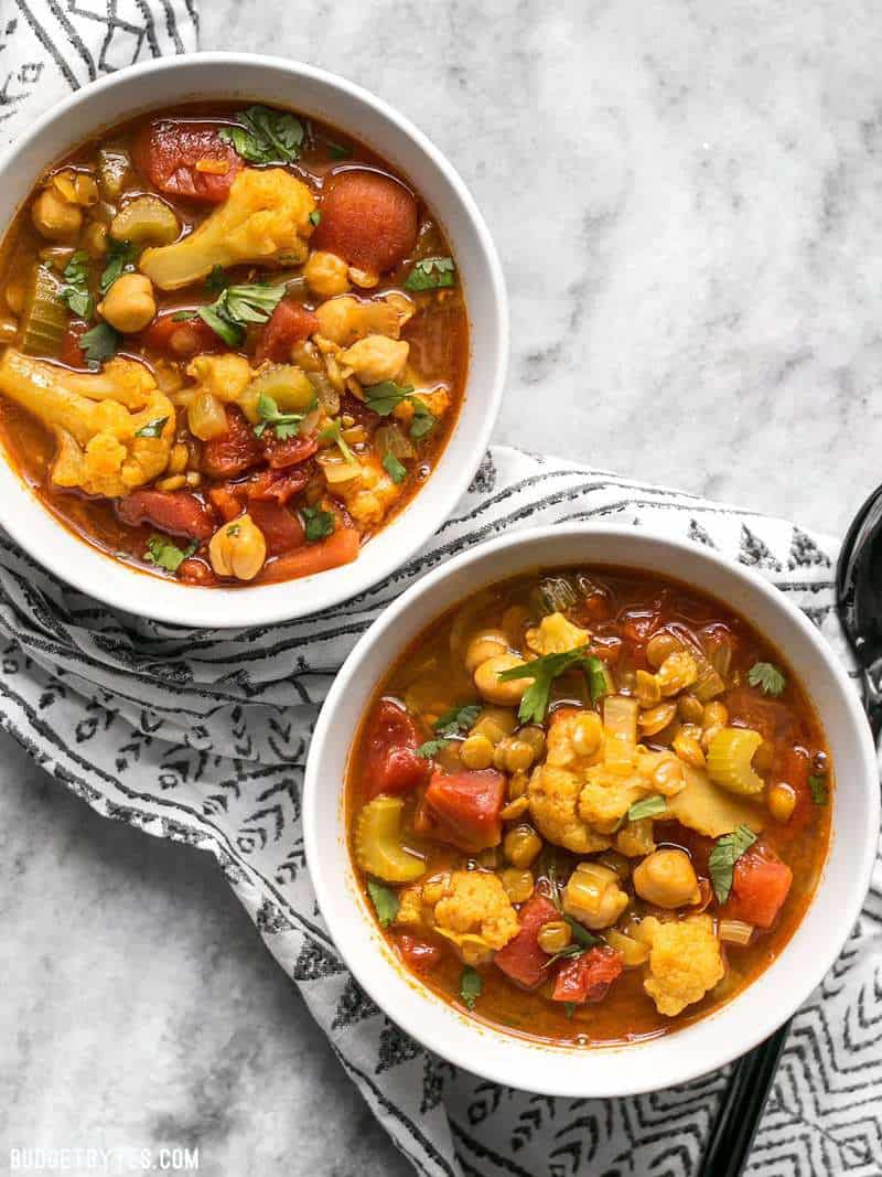 Duas tigelas de lentilha marroquina e guisado de legumes e um guardanapo preto e branco