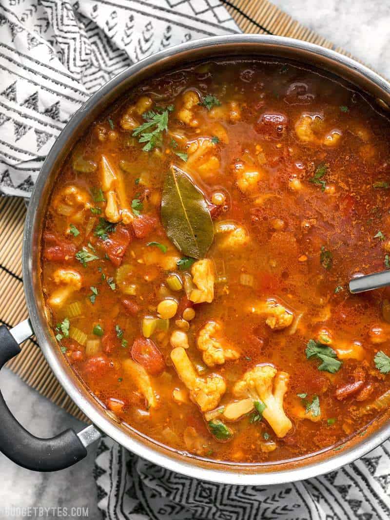 Una gran olla de estofado marroquí de lentejas y verduras recién cocinado, con la hoja de laurel encima