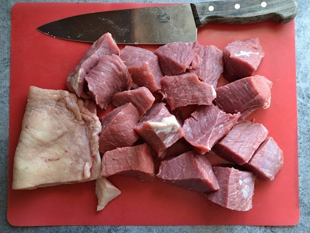 Roast cut into cubes with knife on cutting board 