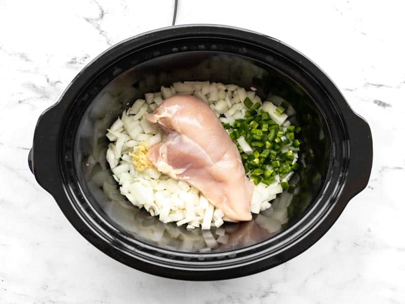 Onion, garlic, jalapeño, and chicken breast in the slow cooker