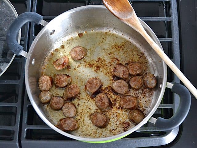 Sautéing sliced sausage in pan to brown all sides