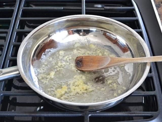 Garlic and Butter in pan on stove top, stirred with wooden spoon