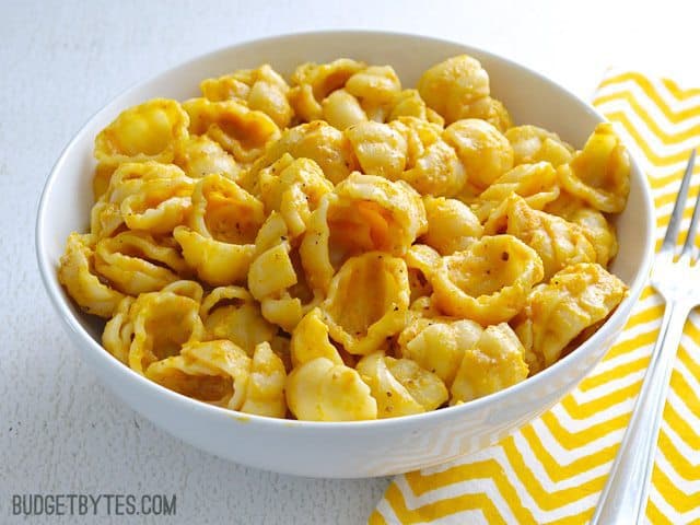 Side view of. a bowl of. Pasta with Creamy Pumpkin Sauce sitting on a yellow chevron napkin with a fork on the side 