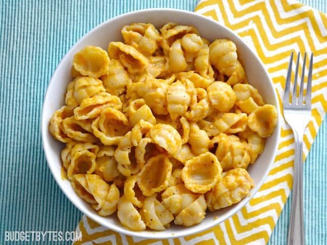 Top view of a bowl of Pasta with Creamy Pumpkin Sauce, sitting on a yellow chevron napkin with a fork on the side 