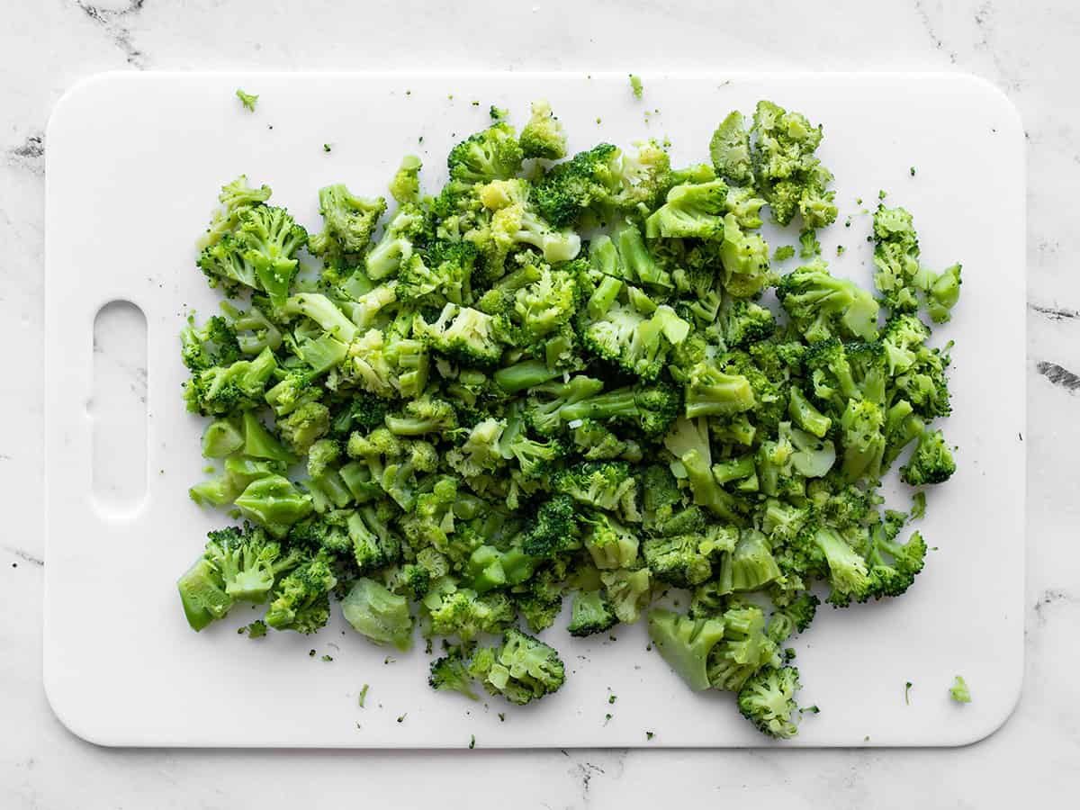 Chopped frozen broccoli florets on a cutting board