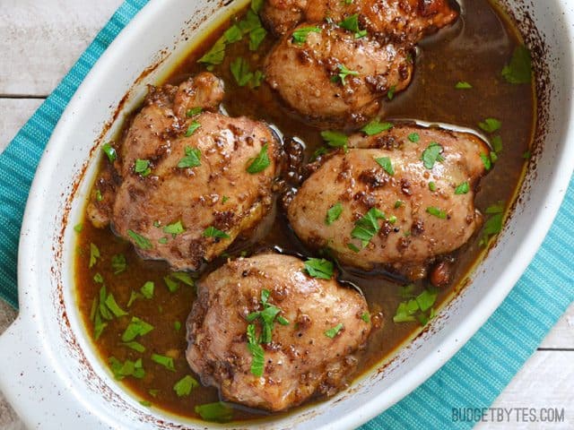 Top view of a dish of Balsamic Chicken Thighs siting on a blue place mat 