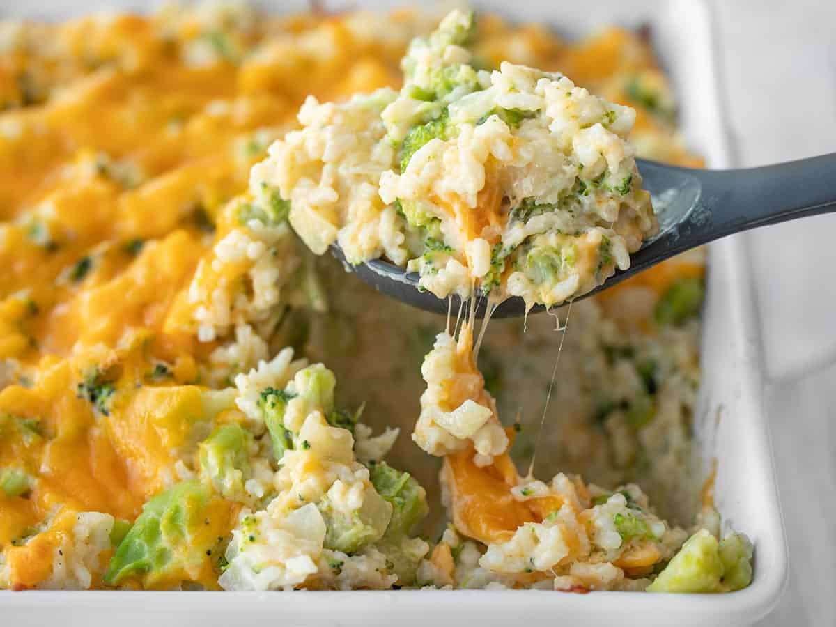 Side view of broccoli cheddar casserole being lifted out of the dish with a spoon