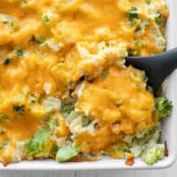 Broccoli cheddar casserole being scooped out of the dish