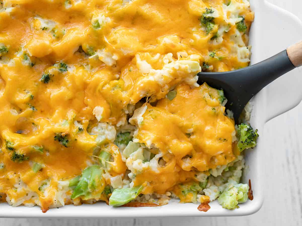 Broccoli cheese casserole being scooped out of the dish