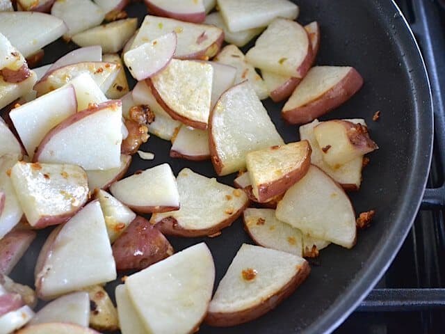 Potatoes added to garlic and oil in skillet to brown