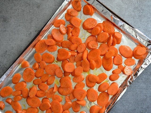 Carrots tossed in olive oil and curry powder and placed on baking sheet lined with tin foil, Ready to Roast