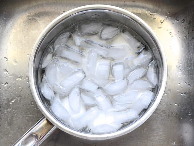 Ice cubes placed in pot of water and eggs to stop cooking (ice bath) 