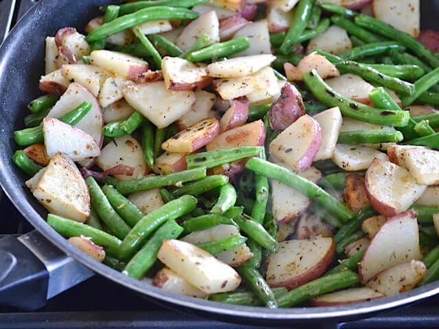 Seasoned potatoes and green beans in skillet 