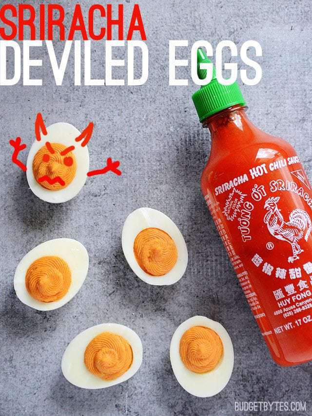 Five Sriracha Deviled Eggs with a bottle of Sriracha, one deviled egg with a face drawn on it like a devil 