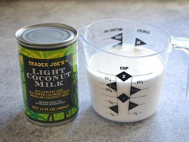 Can of coconut milk with a measuring cup of milk 