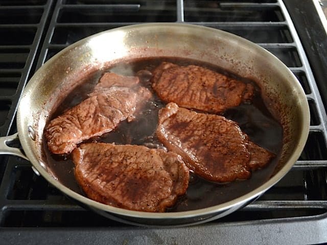 Pork chops added back into skillet with pan sauce 