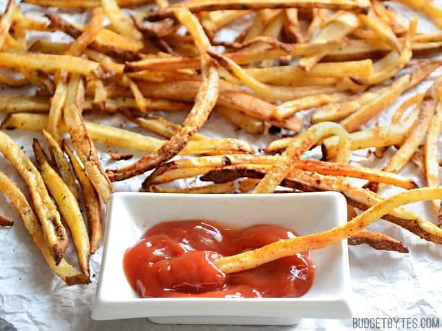Close up of Smoky Garlic Oven Fries being dipped in ketchup 
