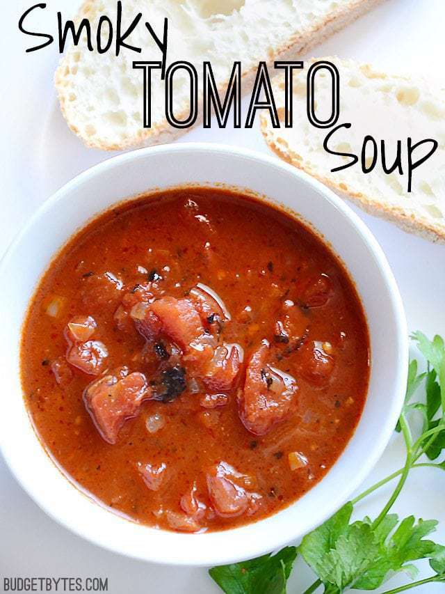 Top view of a bowl of Smoky Tomato Soup with two slices of bread on the side 