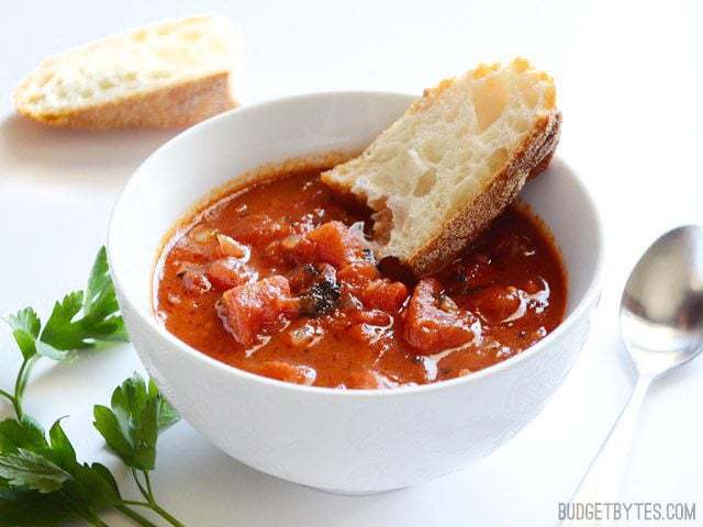 Bread being dipped in a bowl of Smoky Tomato Soup 