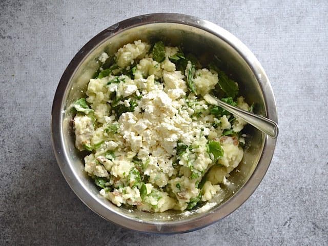 Wilted Spinach and Feta added to potato mixture in mixing bowl 
