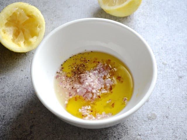 Dressing Iingredients in small mixing bowl with lemon halves in the background 