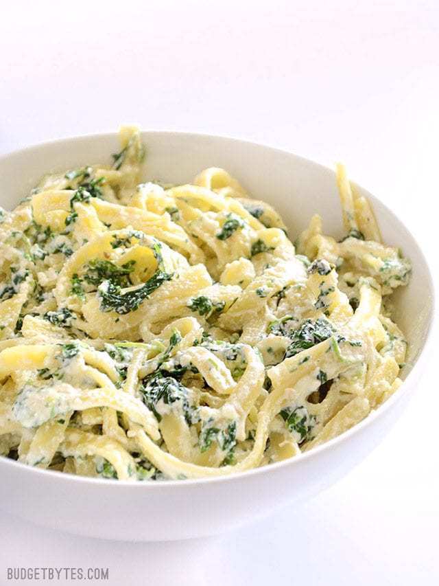 Close up side view of a serving bowl full of spinach ricotta pasta