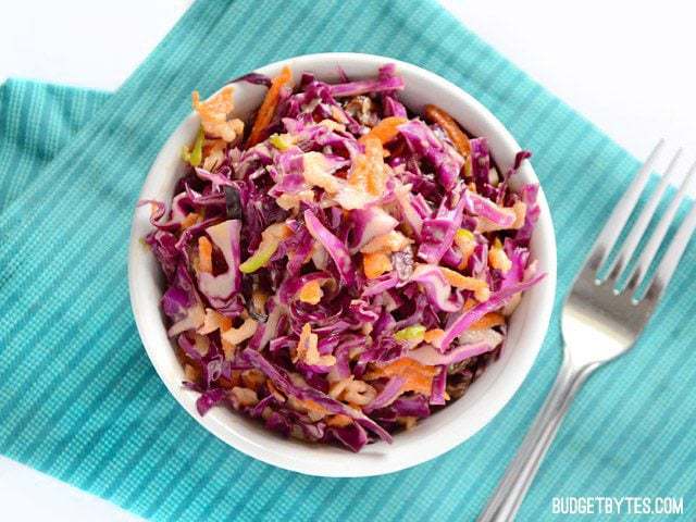 Overhead view of a bowl of Apple Cabbage Slaw on a teal napkin