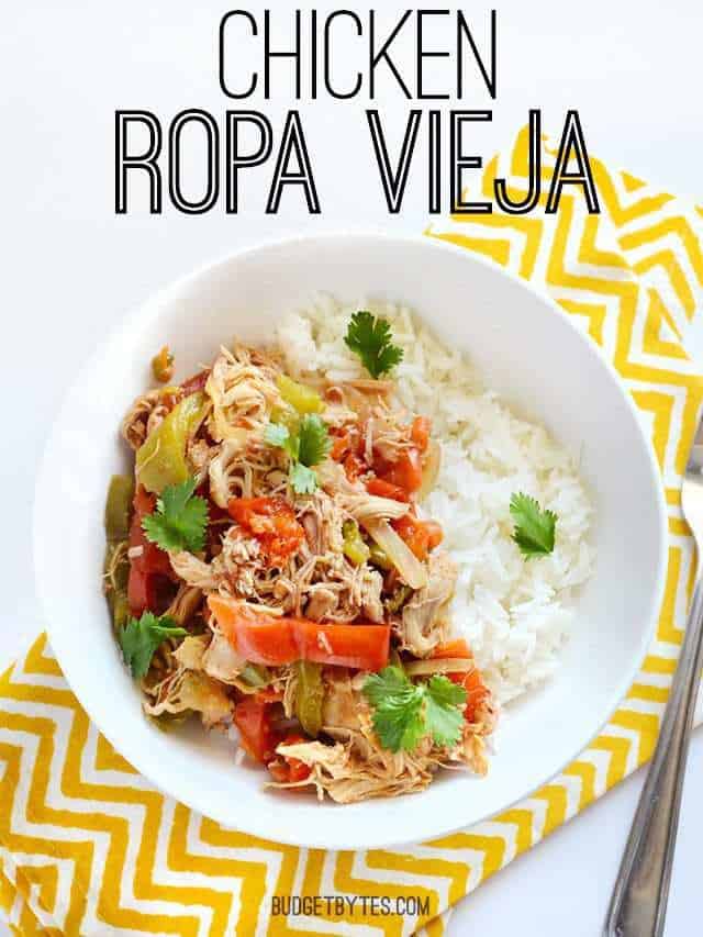 Top view of a bowl of Chicken Ropa Vieja sitting on a yellow chevron napkin with a fork on the side 