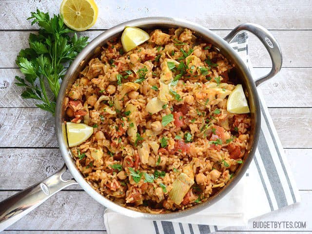 The finished skillet full of Spanish Chickpeas and Rice with lemon wedges and parsley