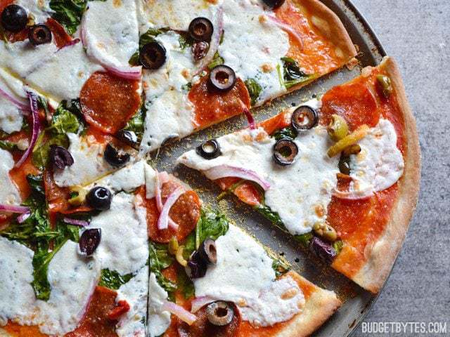 This awesomely thin and crispy pizza crust requires only a few ingredients and about 30 minutes to make. Better and FASTER than take out! Budgetbytes.com Sliced Thin and Crispy Pizza Crust baked with toppings, sliced into pieces