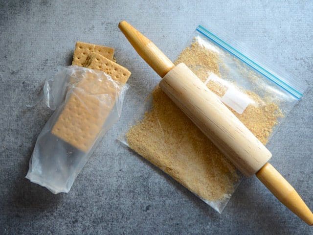 Graham crackers being crushed in a zip top bag with a rolling pin