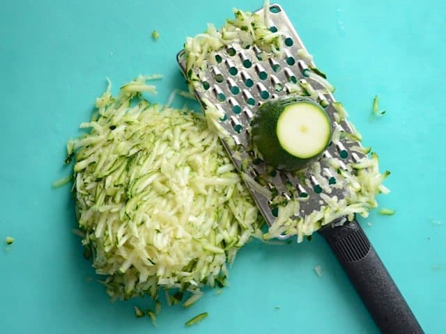 Zucchini being shredded on a cheese grater