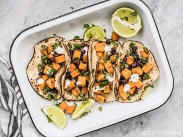 These light and refreshing Sweet Potato Tacos are filled with a simple sweet potato and black bean hash, and topped with a tangy lime crema. BudgetBytes.com