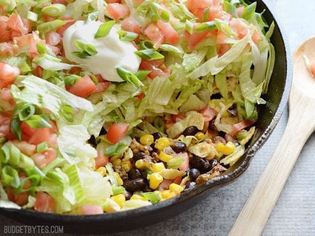 This entire taco salad is served right in the skillet used to cook the seasoned taco beef. Taco Salad Skillet is a fun, fast, and easy weeknight dinner. Budetbytes.com Side view of Taco Salad Skillet with a portion scooped out