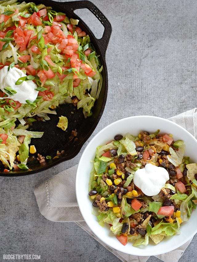 This entire taco salad is served right in the skillet used to cook the seasoned taco beef. Taco Salad Skillet is a fun, fast, and easy weeknight dinner. Budetbytes.com Taco Salad Skillet with a portion served in a bowl on the side