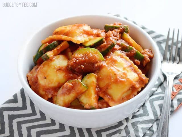 Side view of a bowl of Zucchini Sausage Ravioli on a zig zag napkin