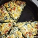 A close-up of creamy spinach and artichoke pizza slice.