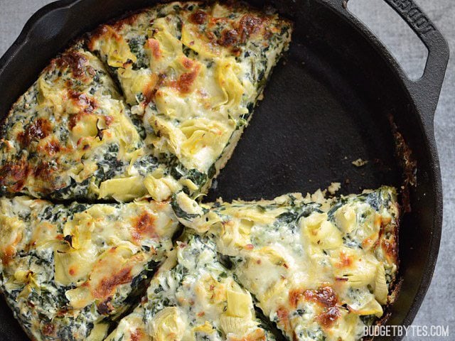 Close up of the baked and sliced Creamy Spinach Artichoke Pizza, with one slice missing