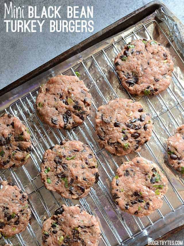 Unbaked Mini Black Bean Turkey Burgers on a baking sheet fitted with wire cooling racks