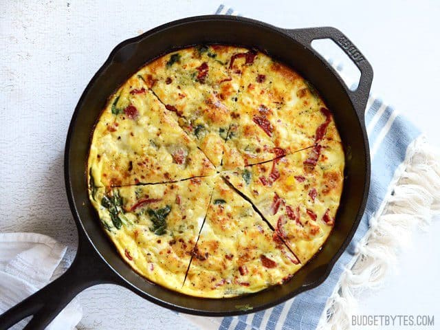 Overhead view of the Roasted Red Pepper and Feta Frittata in a skillet, cut into slices