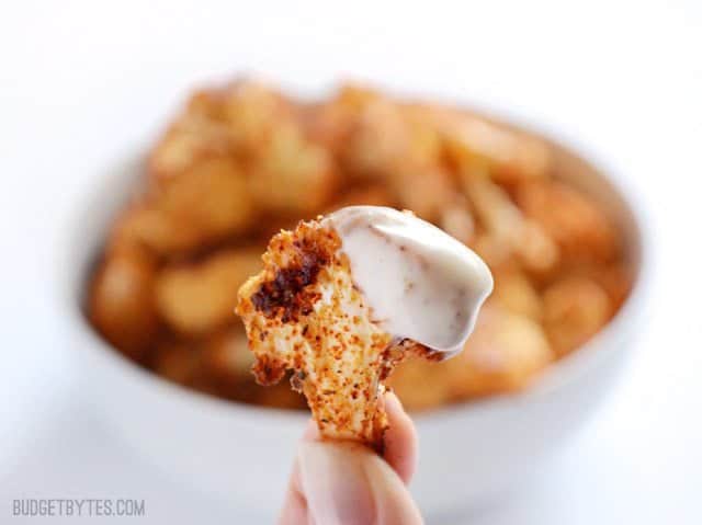 Smoky Parmesan Roasted Cauliflower is an easy, smoky, and savory side dish or snack for dipping in your favorite sauces. Step by step photos. Budetbytes.com Close up of one cauliflower floret dipped in ranch.