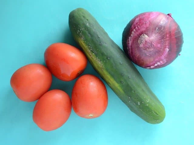 Tomato Cucumber and Red Onion on a blue cutting board