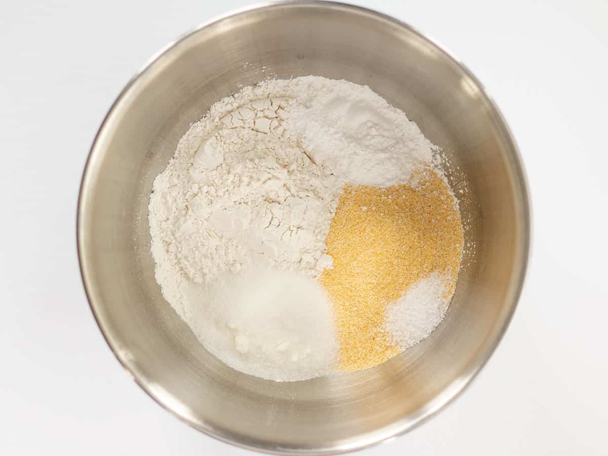 Dry ingredients for cornbread in a metal bowl.
