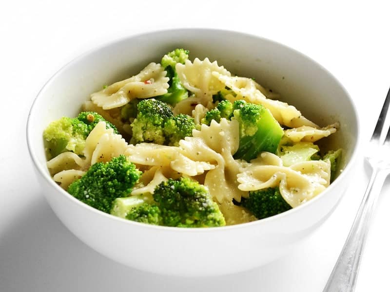 Side view of a bowl full of bowties and broccoli