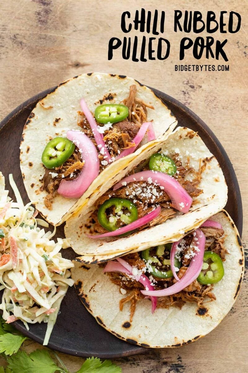 Three pulled pork tacos on a plate with slaw