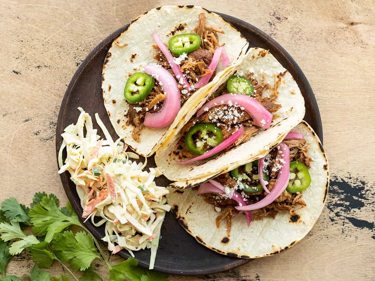 Three pulled pork tacos on a plate with coleslaw