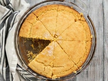 Overhead view of cornbread in the baking dish with a slice missing.