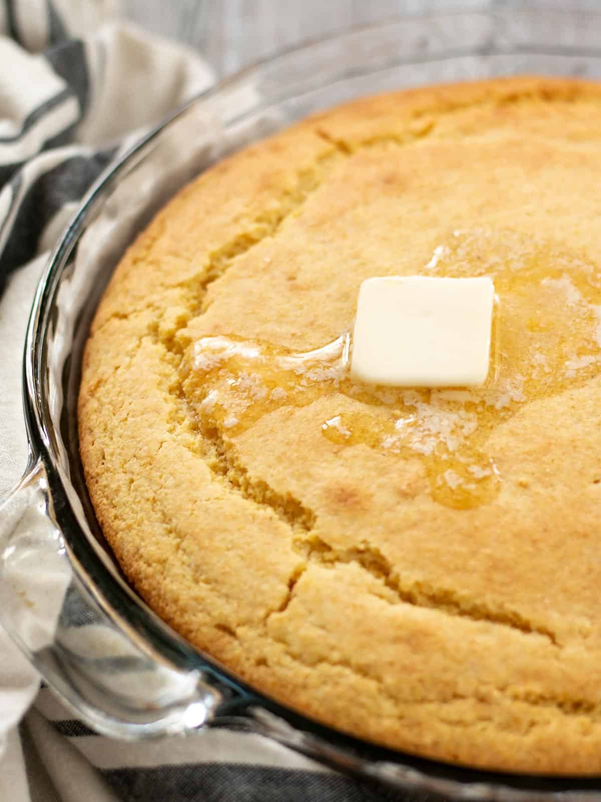 Close up side view of butter melting on top of baked cornbread.