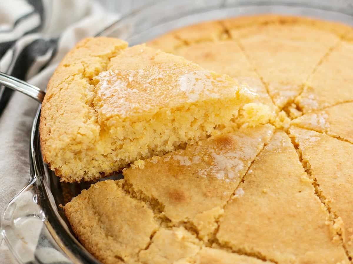 Side view of a piece of cornbread being lifted out of the baking dish.