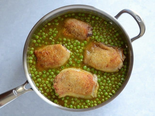 Chicken added back to the skillet with the broth and peas